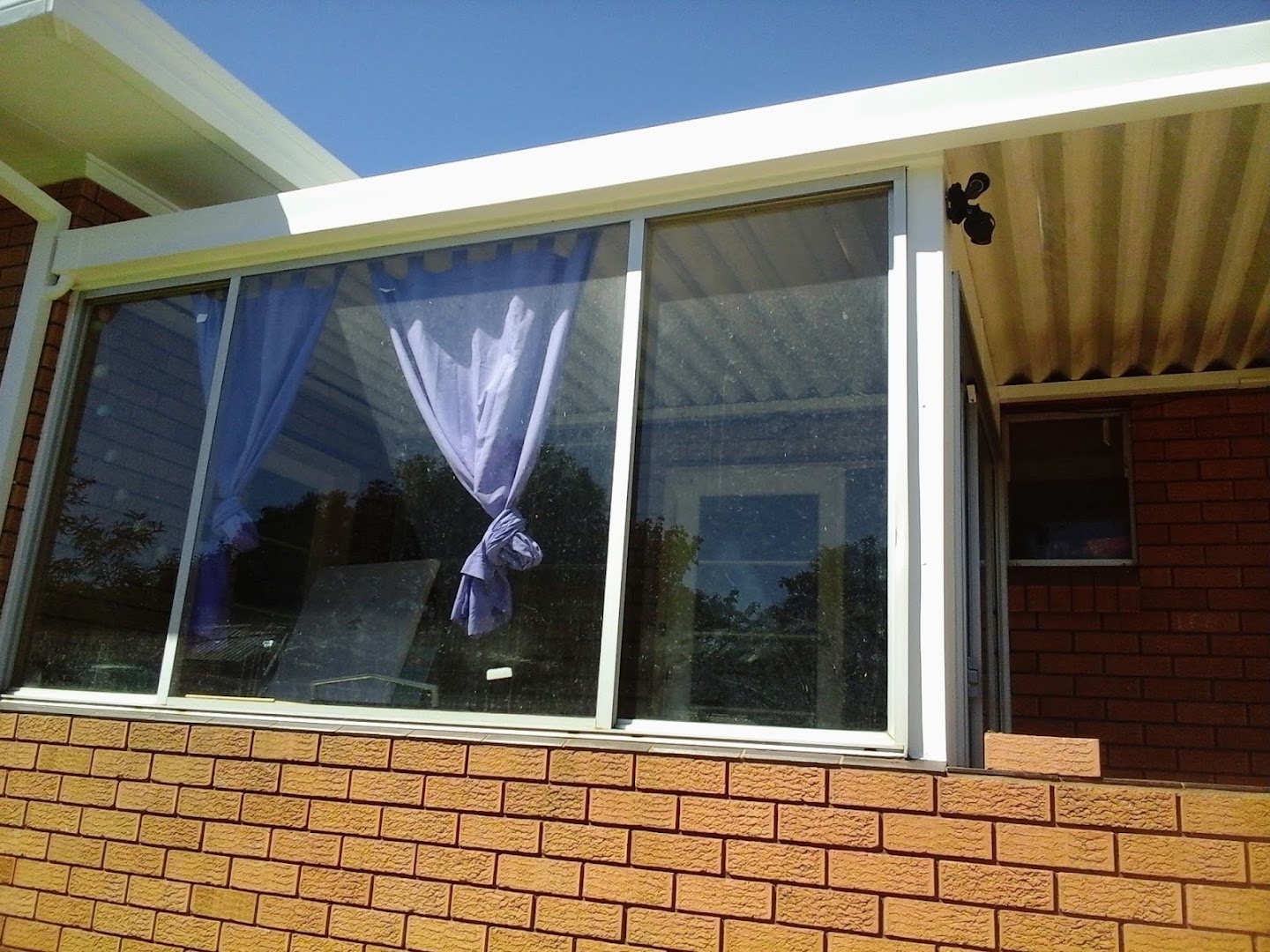A replaced window and awning set into a brick wall under a clear sky
