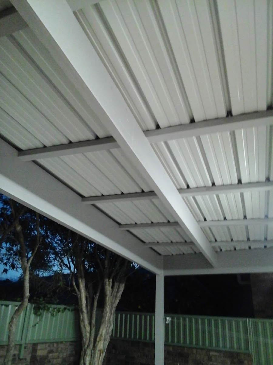 The underside of a new white patio roof looking out to the garden