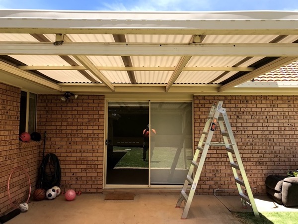 A timber pergola frame under construction beside a brick wall