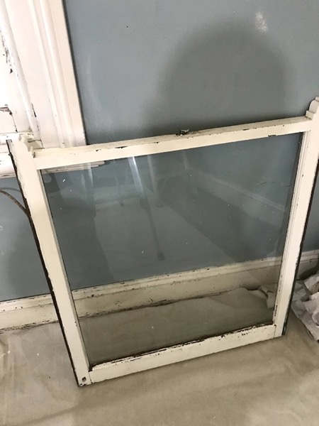 An old window sash removed and standing on the ground