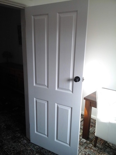 A new white panel door hung in its frame