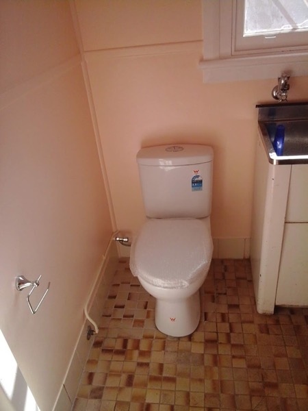 A toilet suite in a bathroom with a patterned tiled floor