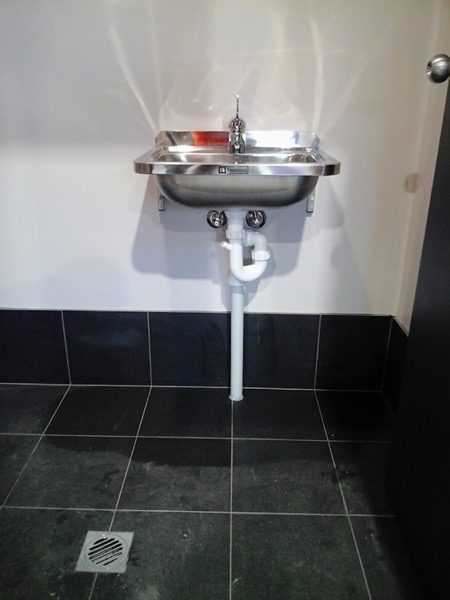 A stainless steel wall basin with exposed pipework