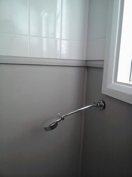 A grab rail fitted to a white tiled bathroom wall