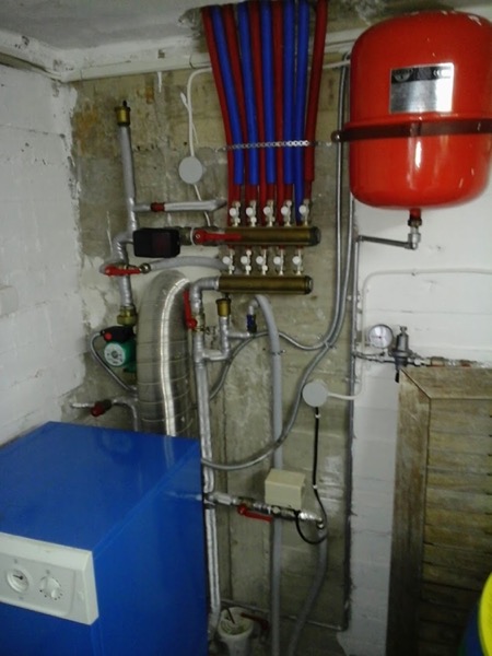 A manifold with a red expansion vessel and blue supply lines