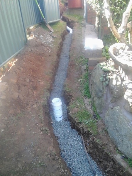 A gravel-filled drainage trench running beside a path