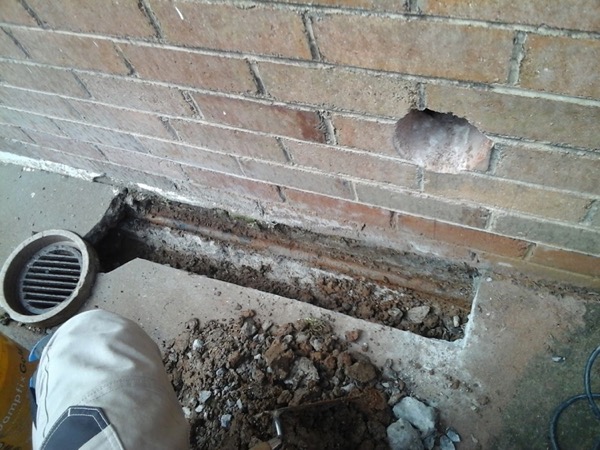 A brick wall with a rendered patch and a wall vent