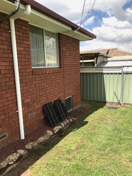 A brick wall with a downpipe running to a drainage point